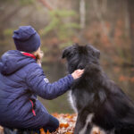 Kind und Hund Rueckenansicht schauen in die Ferne