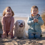 Kinder und Hund lachend am Strand